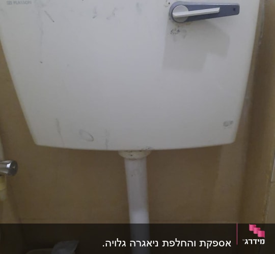 ניאגרה לבנה עם ידית מתכת בחדר אמבטיה